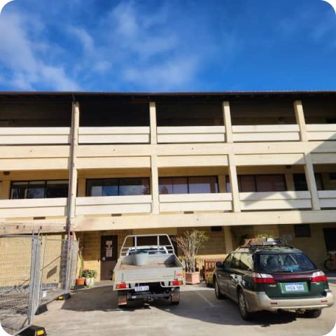 Two cars are parked in front of a large building