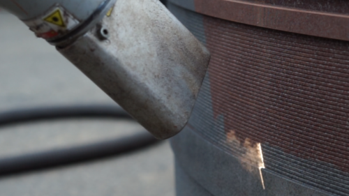 A close up of a machine cleaning a piece of metal.