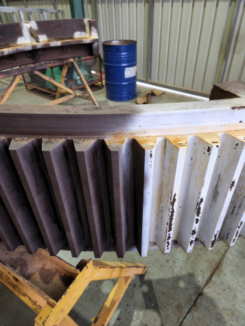 A large metal object is sitting on top of a wooden table next to a blue barrel.