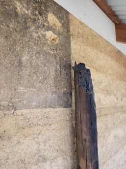 A wooden post is leaning against a concrete wall.