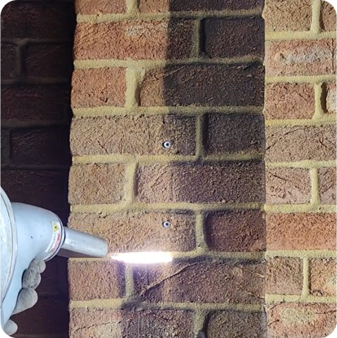 A person is spraying a brick wall with a light