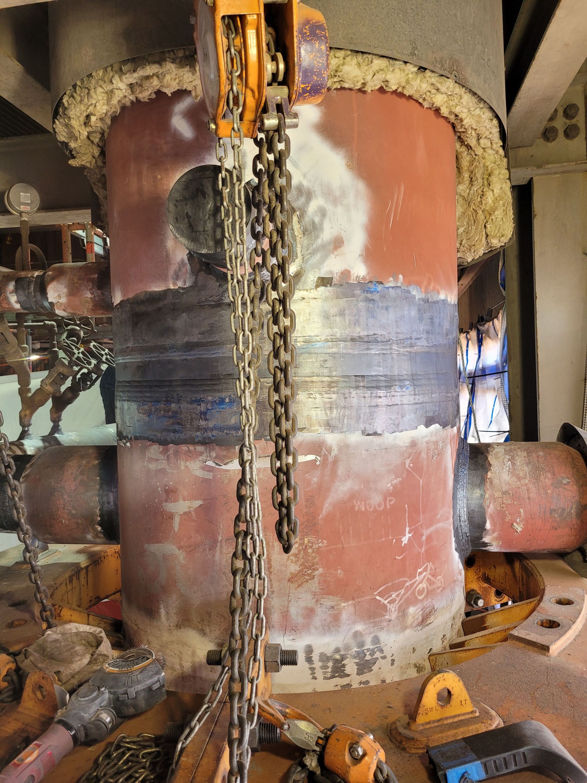 A chain is hanging from a large metal pipe.