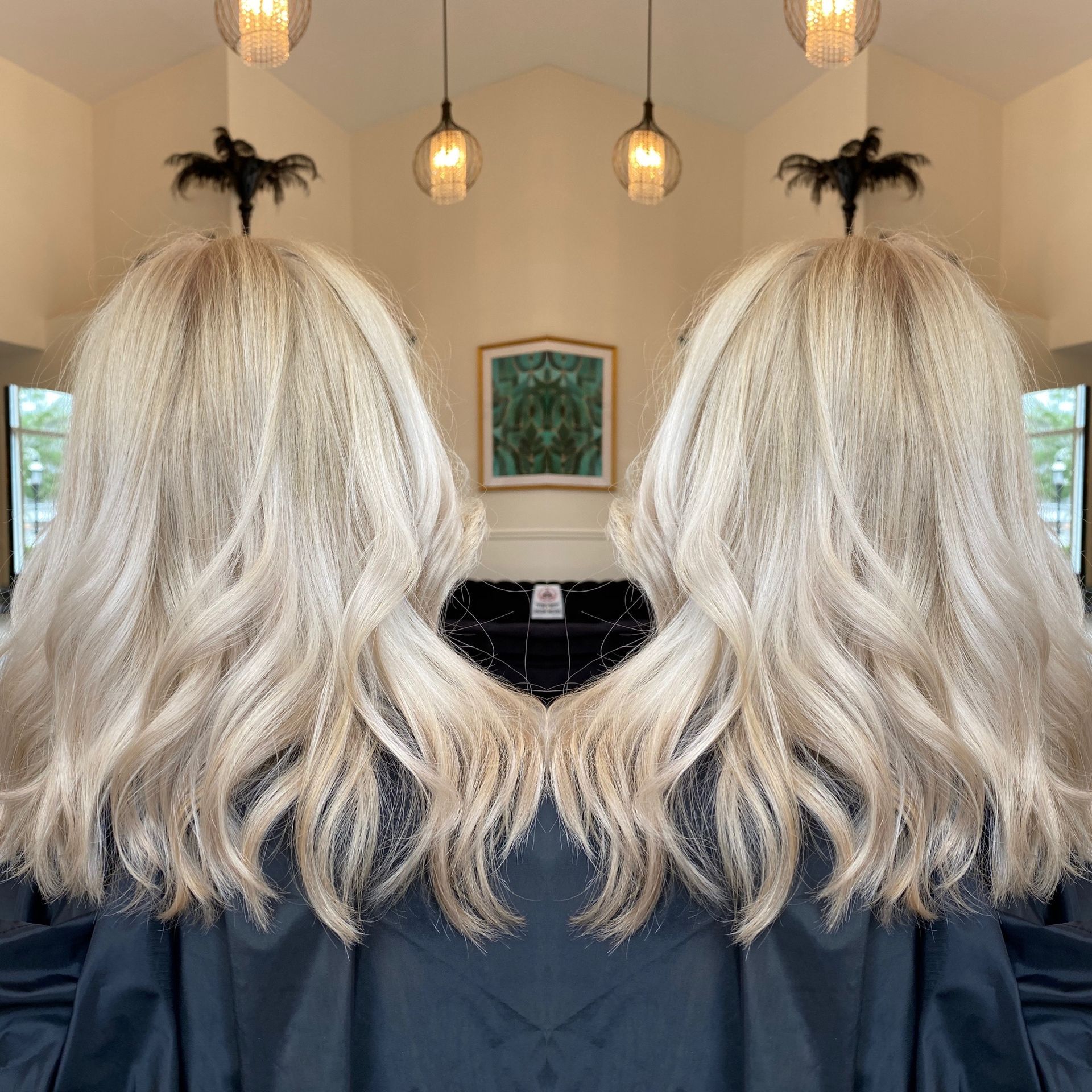 A woman with blonde hair is sitting in a chair in front of a mirror.
