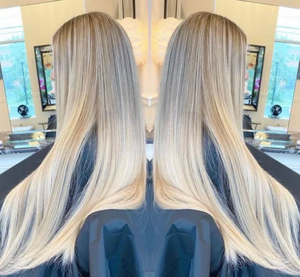 A woman with long blonde hair is sitting in front of a mirror.