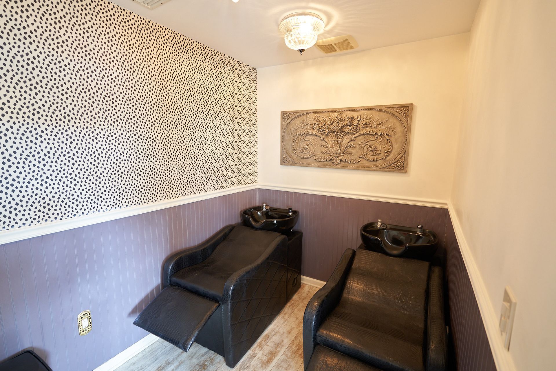 A room with two chairs and two sinks in it.