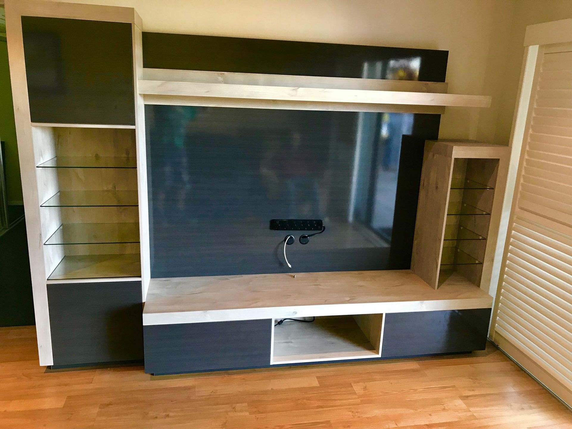 A Large Flat Screen Tv is Sitting on Top of a Wooden Entertainment Center — Tefa Kitchens & Joinery in Rutherford, NSW 