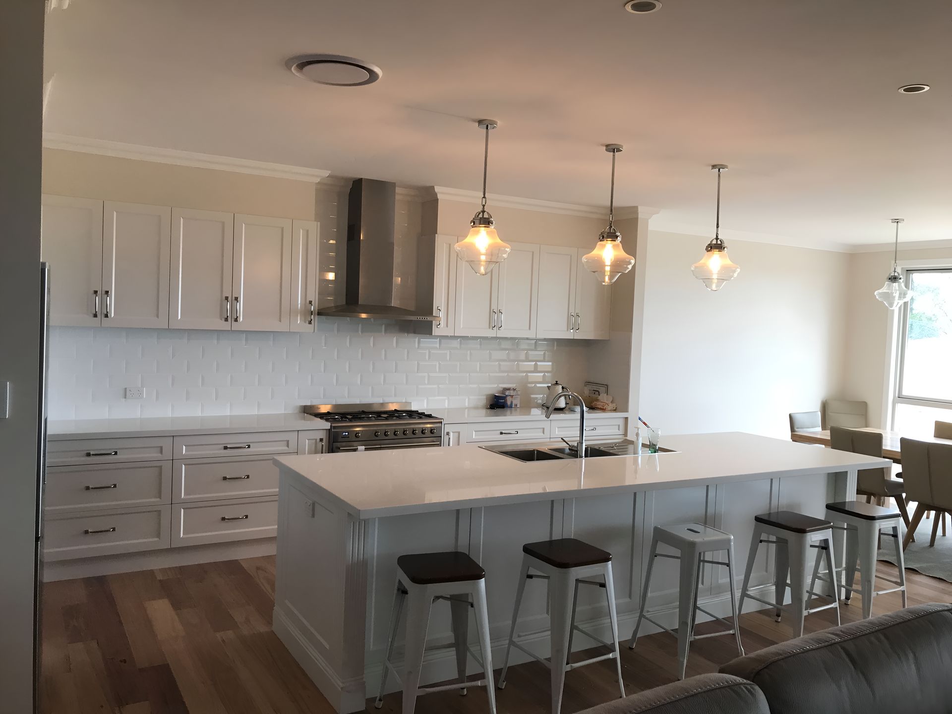 A Kitchen With White Cabinets, Stools and a Large Island — Tefa Kitchens & Joinery in Rutherford, NSW