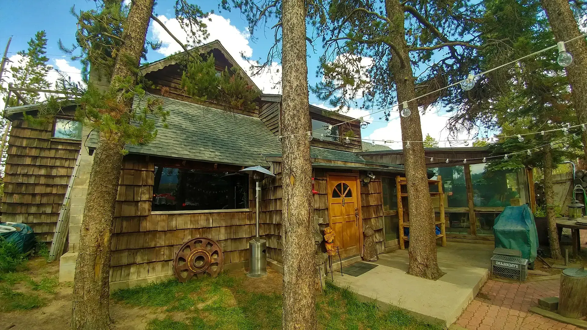 A wooden house is surrounded by trees on a sunny day.