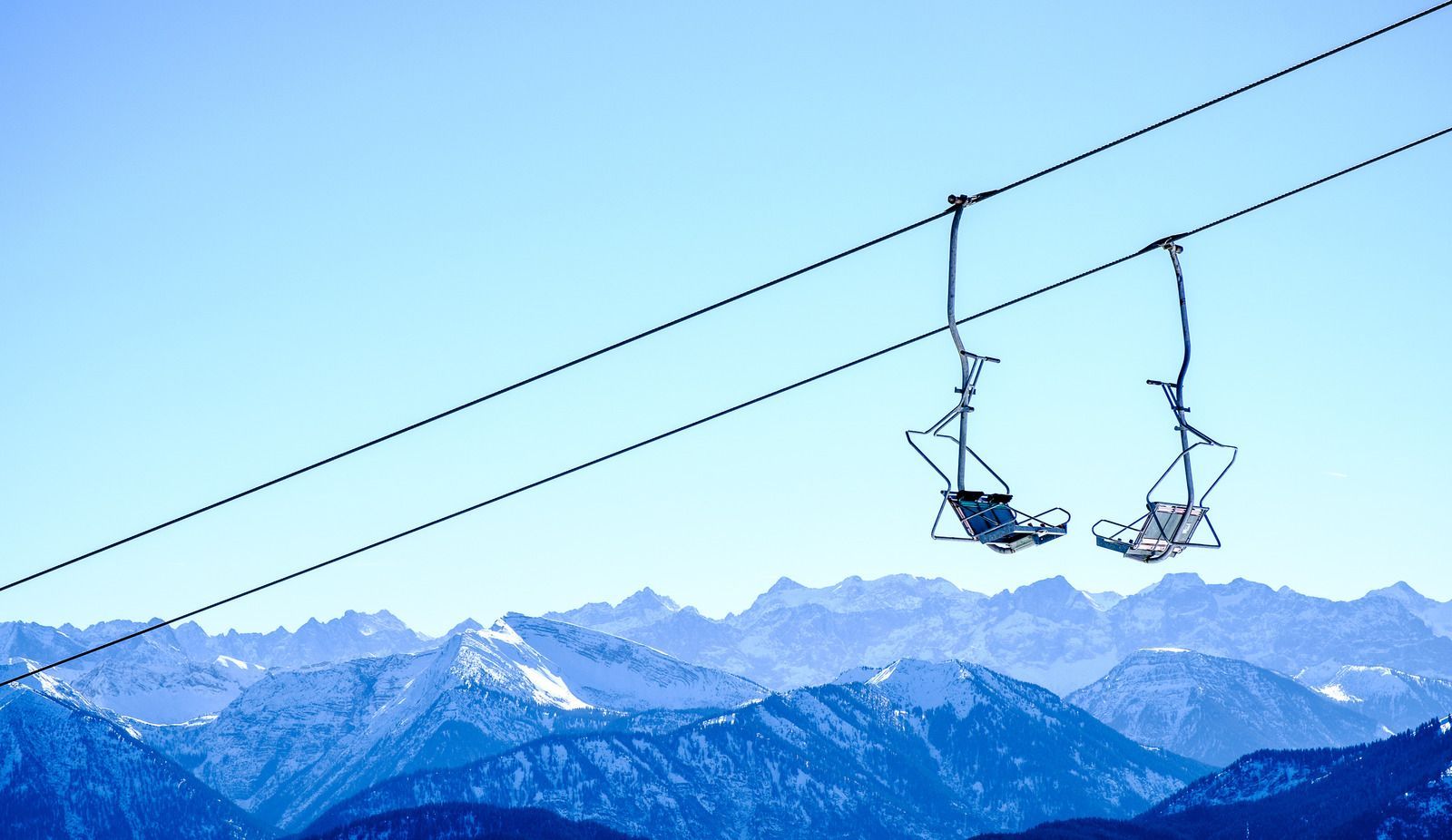 Two people are riding a ski lift in the mountains.