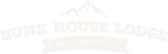 A white logo for junk house lodge with a mountain in the background.
