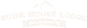 A white logo for junk house lodge with a mountain in the background.