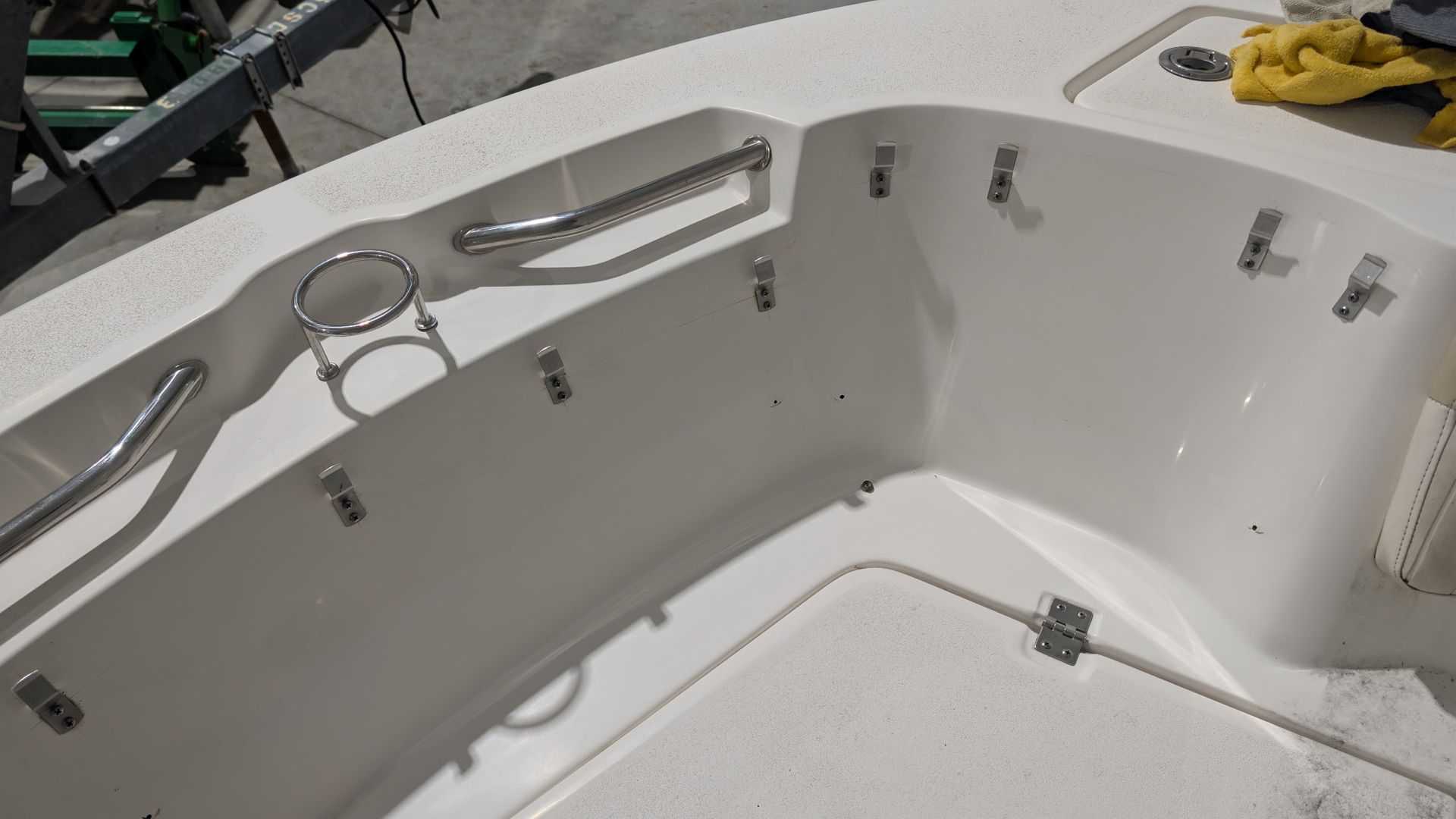 White hot tub interior with built-in seats, handrails, and cleaning cloths on the rim