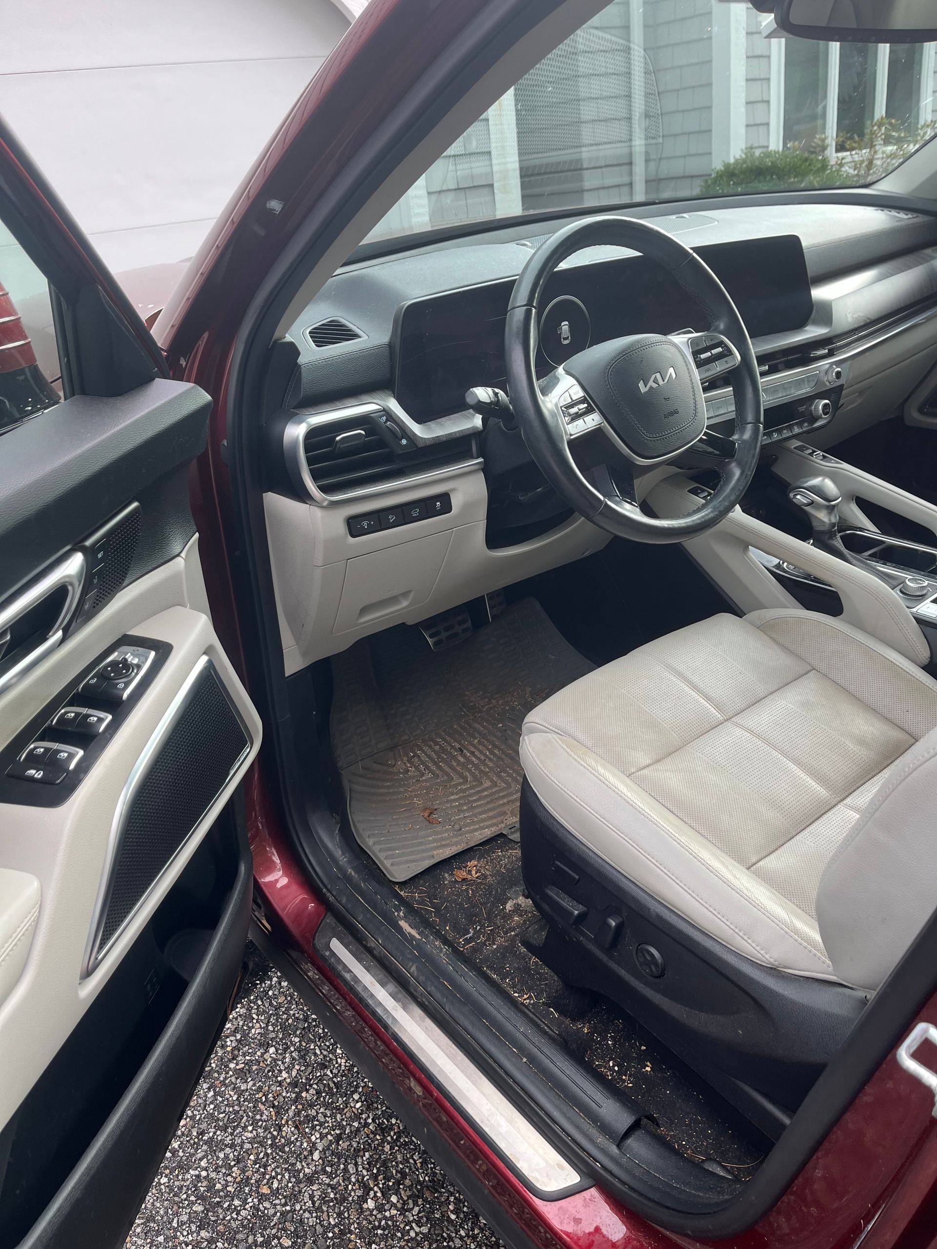 Open driver’s door showing a maroon car interior with beige seats and dashboard