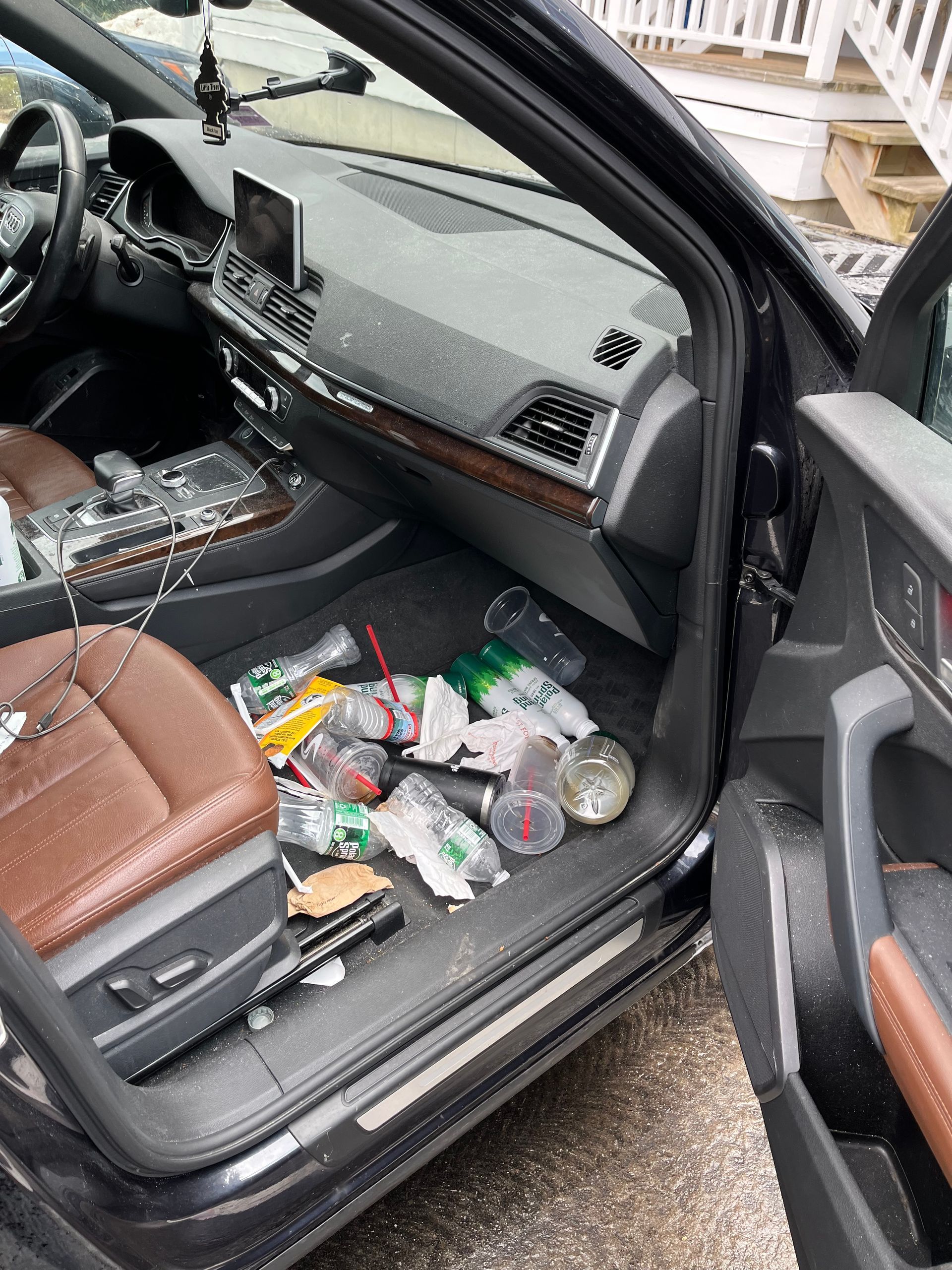 Car interior with front passenger door open, dashboard visible, and litter scattered on the floor.