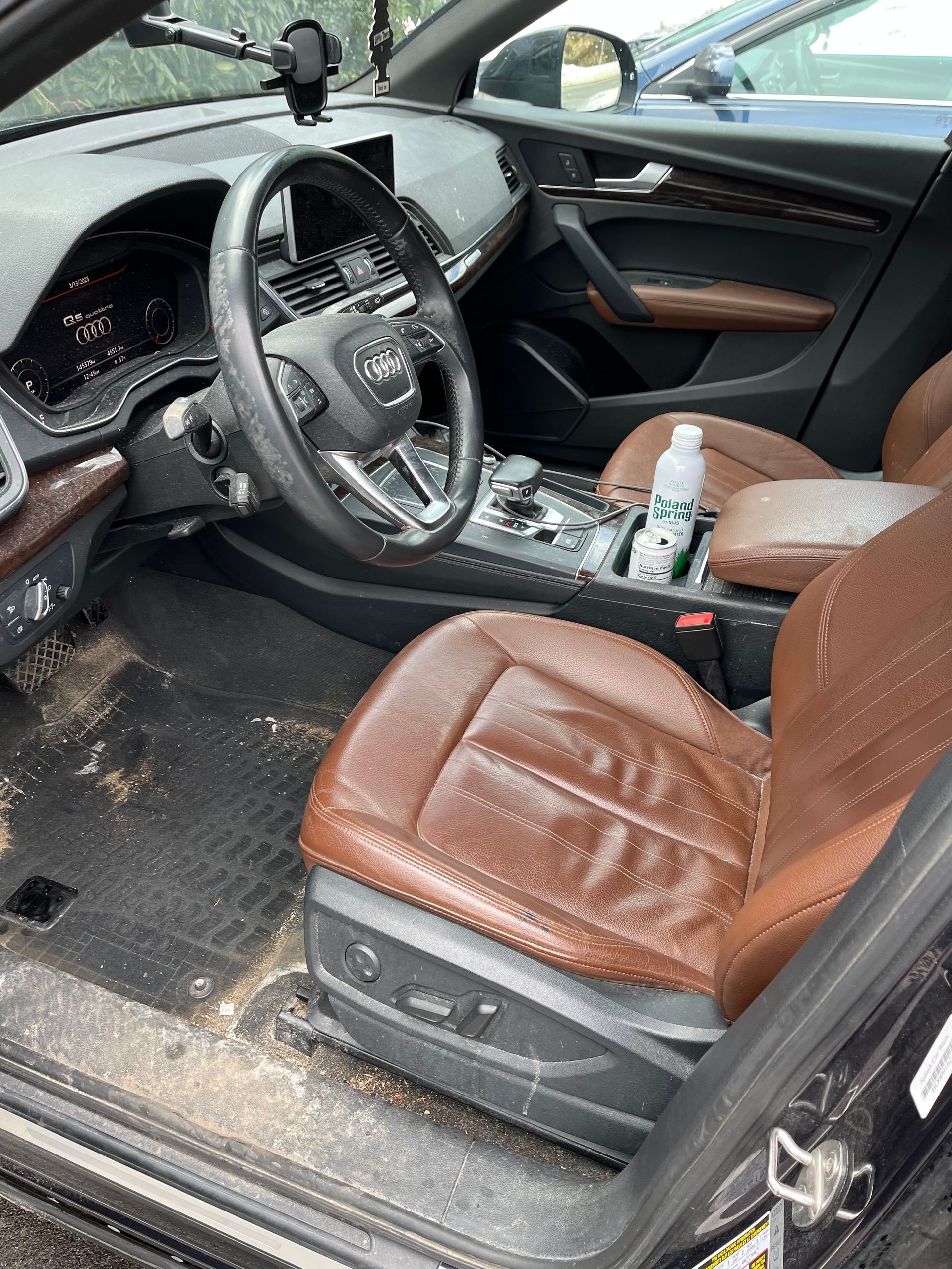 Car interior with brown leather seats and a damaged, dirty floor on the driver’s side