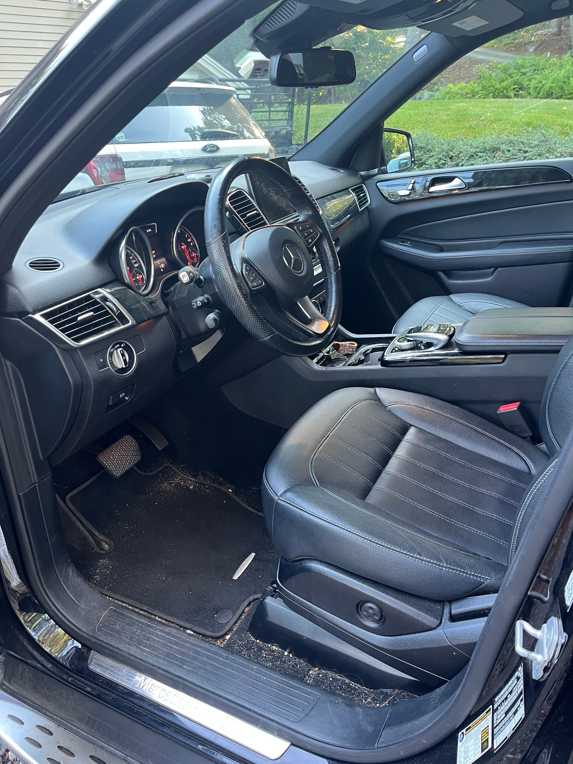 Open car door showing black leather front seat and dashboard interior with a phone holder on the console