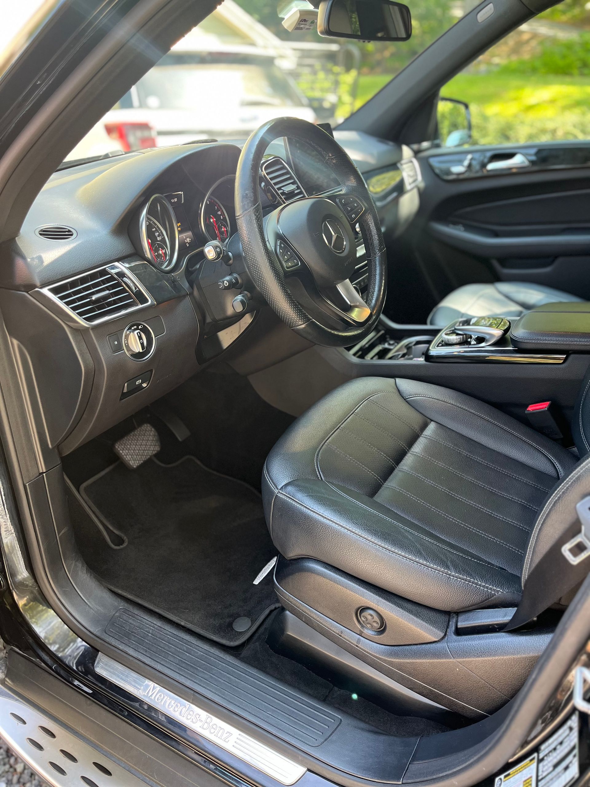 Open car driver’s seat and dashboard with black leather interior and steering wheel