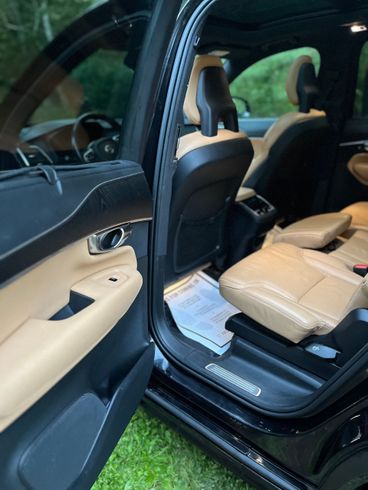 Open car door showing a beige leather interior and front seat area.