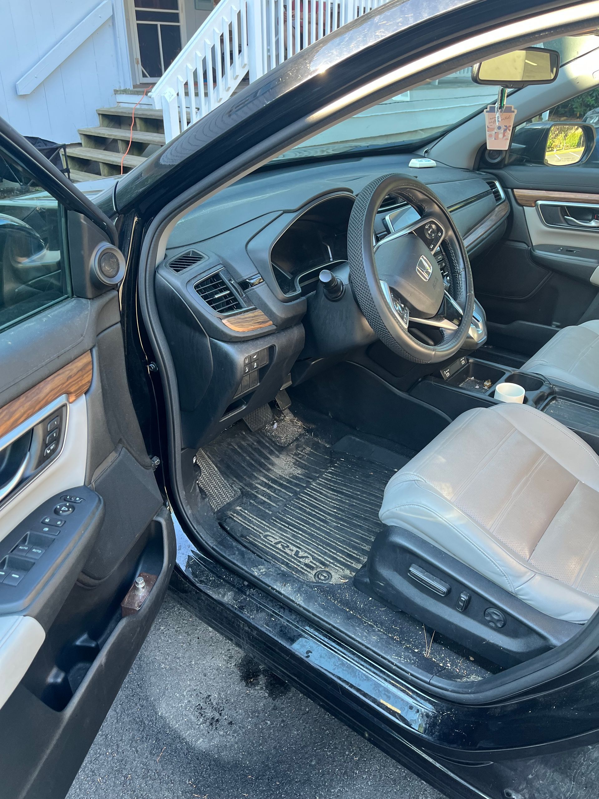 Open car door showing black interior and gray front seat with steering wheel visible