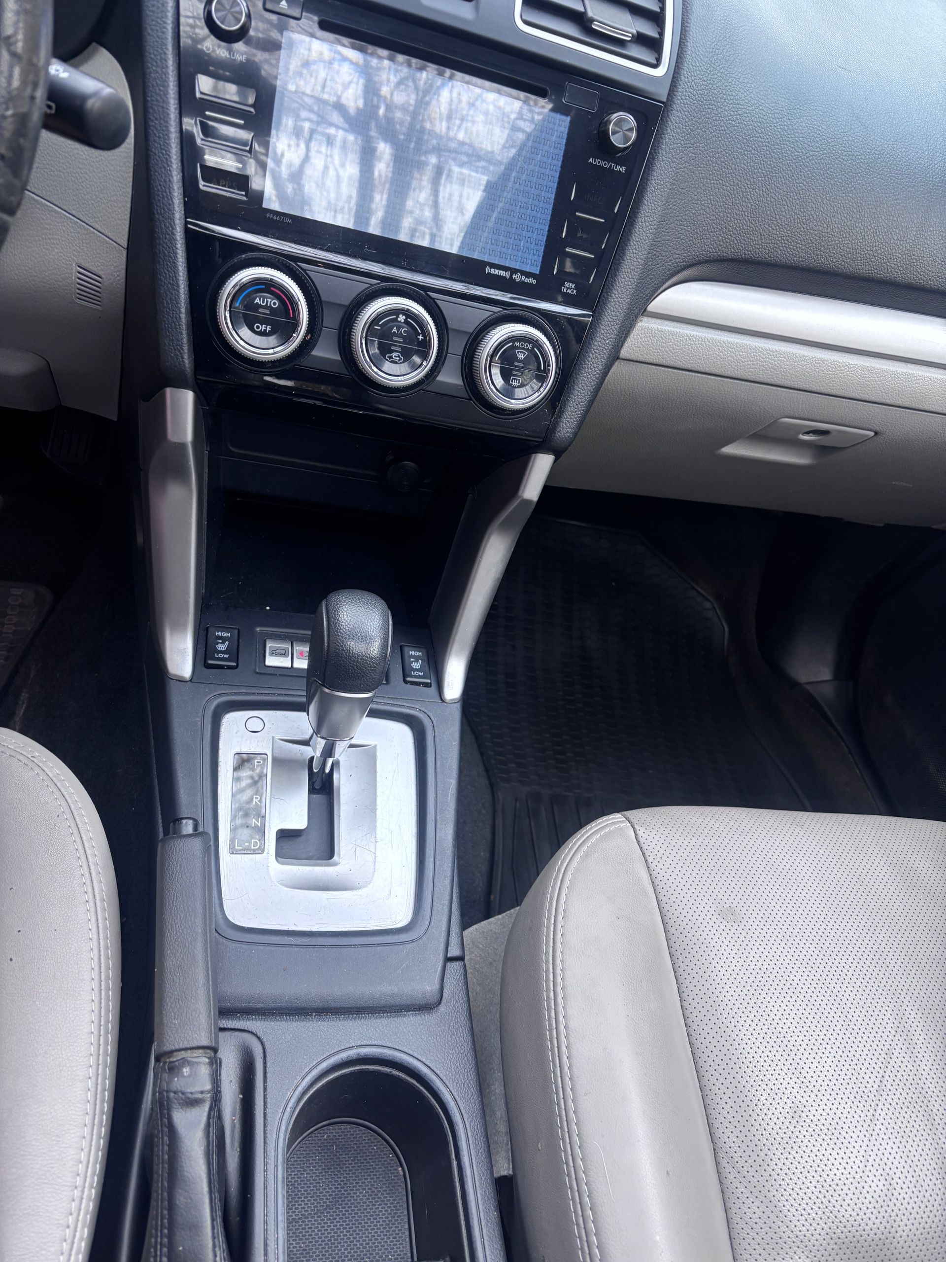 Car interior with touchscreen, climate controls, gear shifter, and front seats visible