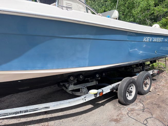Blue boat on a trailer parked beside a paved road