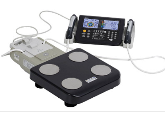 Un analizzatore di composizione corporea dotato di una piattaforma con bilancia nera, quattro elettrodi e un monitor portatile collegato.