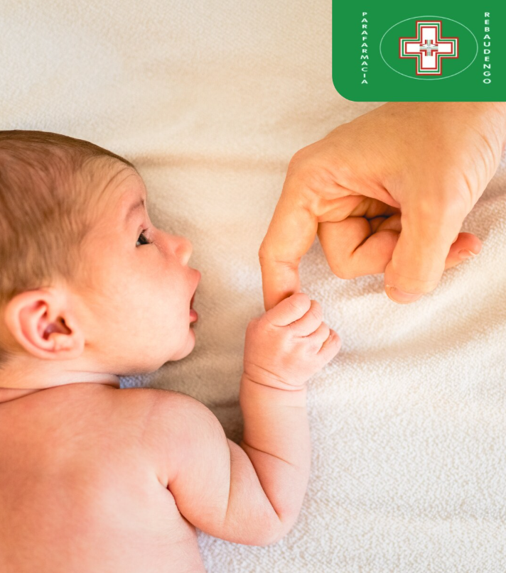 Un neonato allunga la mano per afferrare un grande dito di un adulto, su uno sfondo tenue e chiaro.