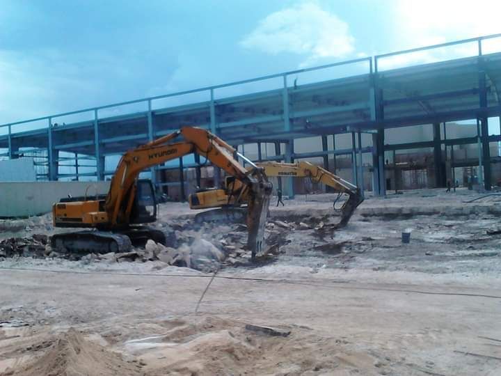 Una excavadora amarilla está destruyendo un edificio en una obra en construcción.