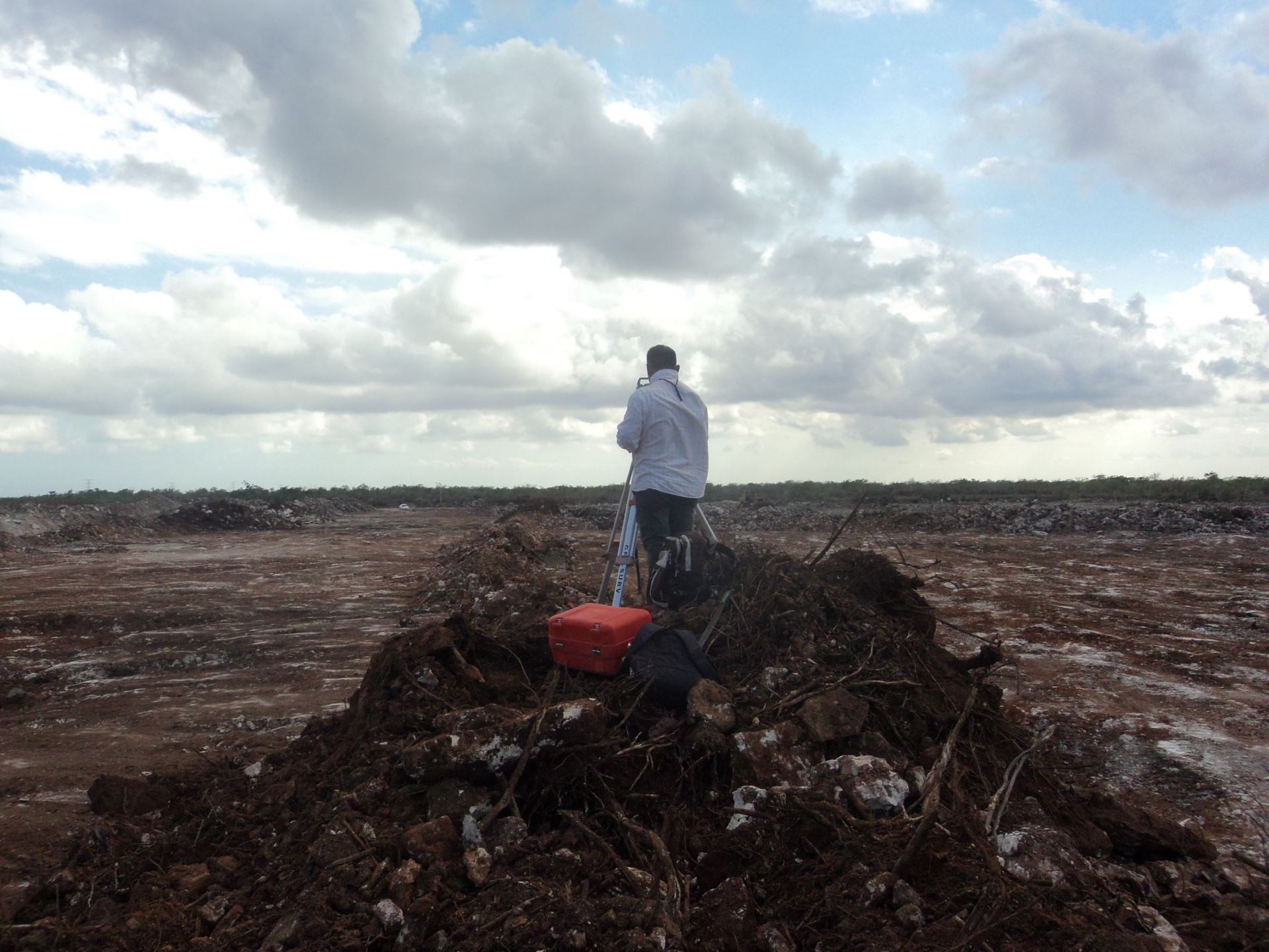 Un hombre está parado encima de un montón de tierra en un campo.