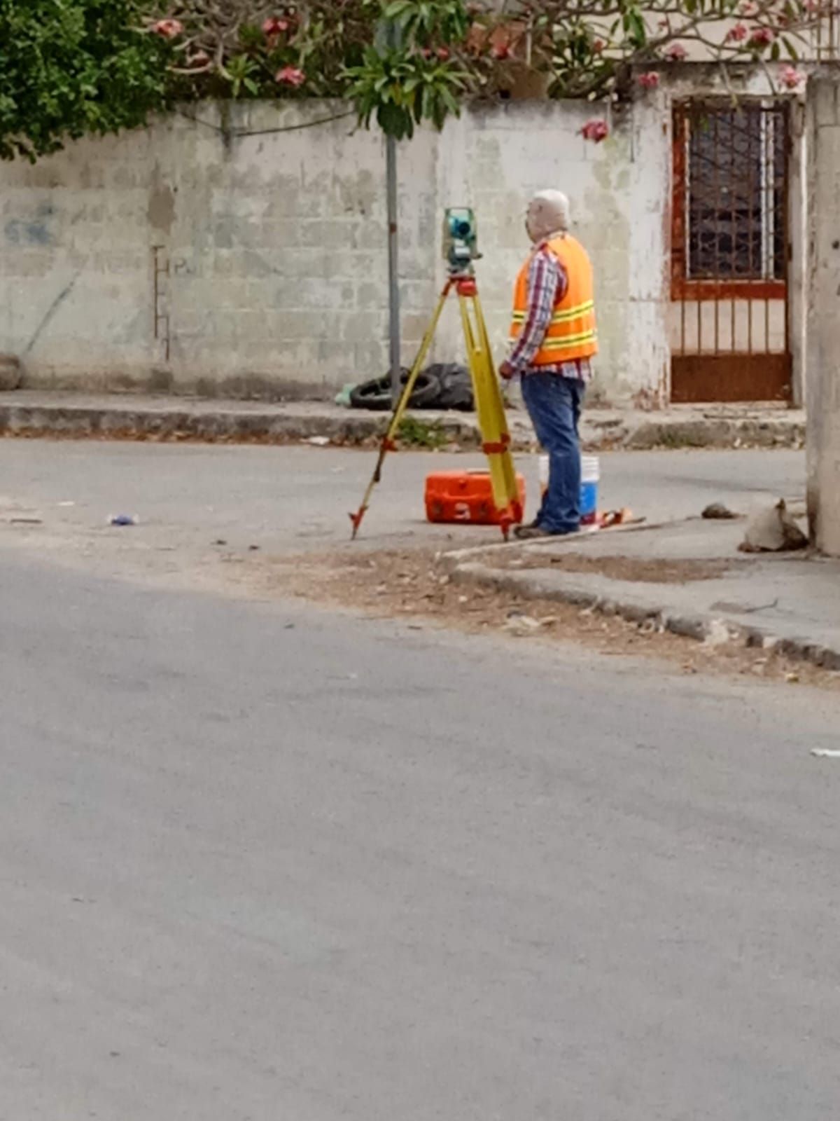 Un hombre está parado al costado de la carretera usando un trípode.