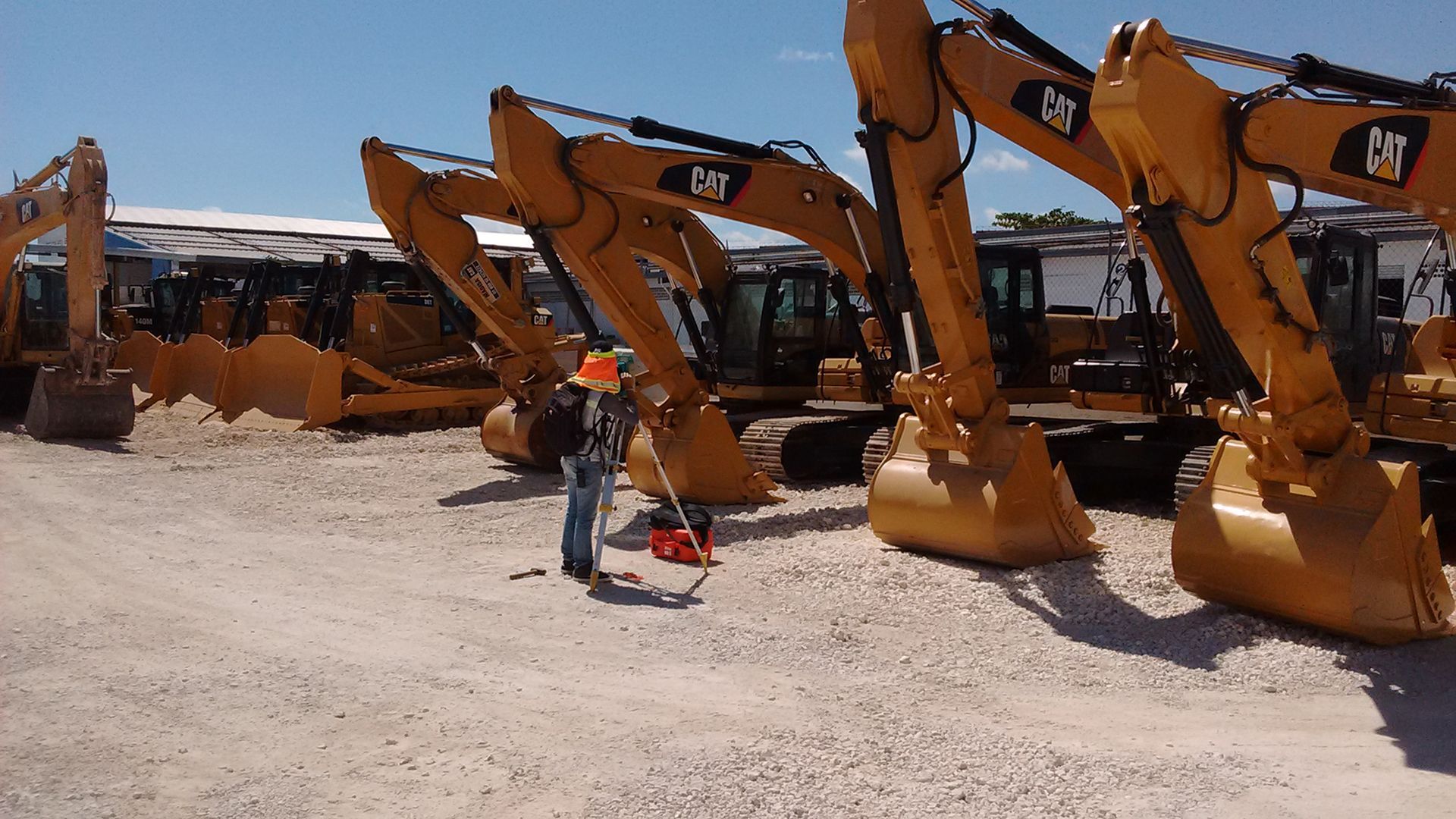 Un hombre está parado frente a una fila de excavadoras de gato.