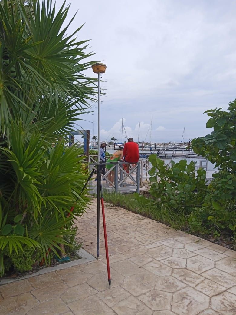 Un hombre con una camisa roja está sentado en una barandilla con vistas a un cuerpo de agua.
