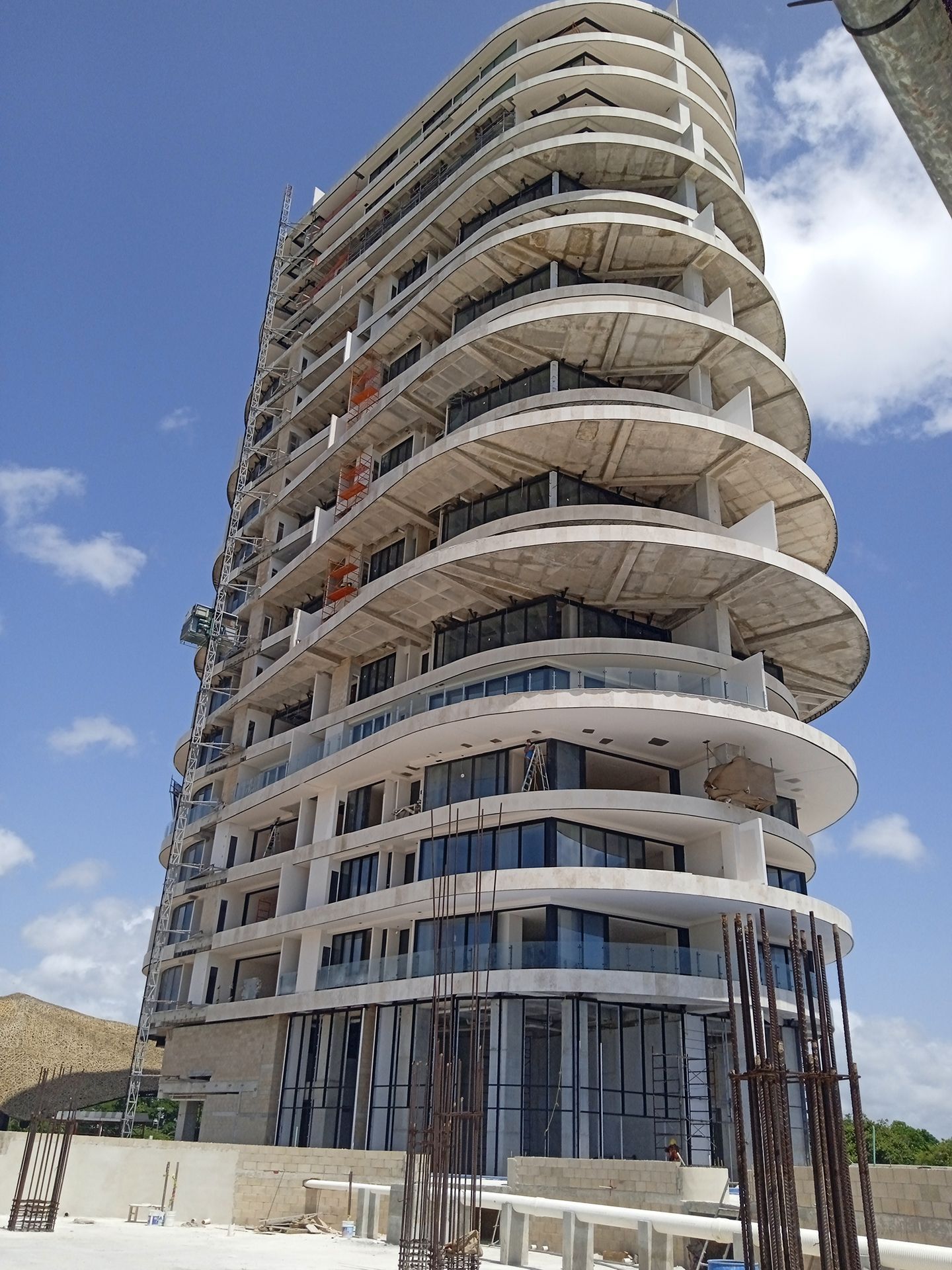Un edificio alto en construcción con un cielo azul de fondo.
