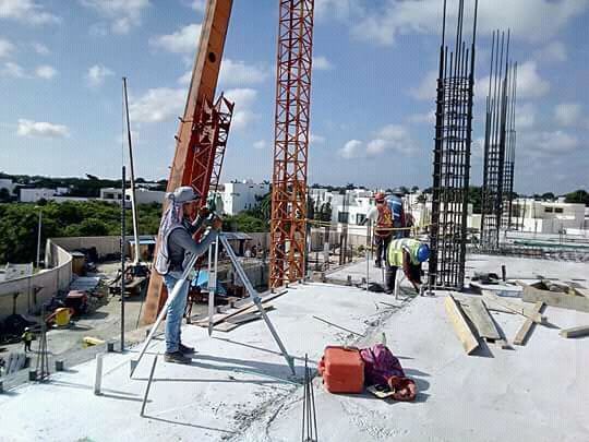 Un hombre está parado sobre un trípode en la parte superior de un edificio en construcción.