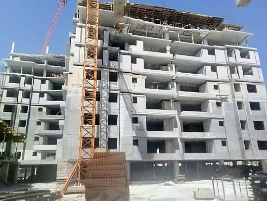 Un gran edificio en construcción con una grúa delante de él.
