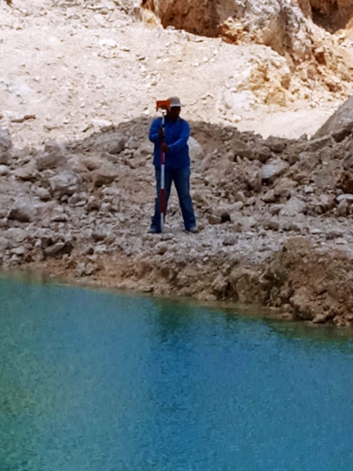 Un hombre con una chaqueta azul está parado junto a un cuerpo de agua.