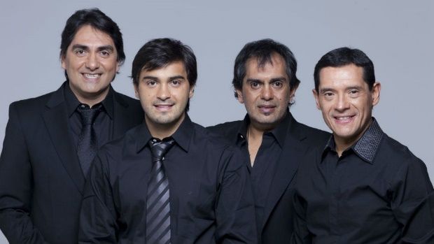 Cuatro hombres con camisas negras y corbatas posan para una fotografía.