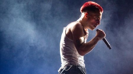 Un hombre pelirrojo está cantando en un micrófono en un escenario.