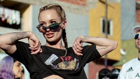 Una mujer que lleva gafas de sol y un top corto está parada frente a un edificio.
