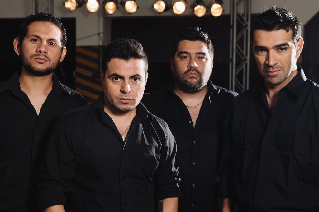 Cuatro hombres con camisas negras están parados uno al lado del otro.