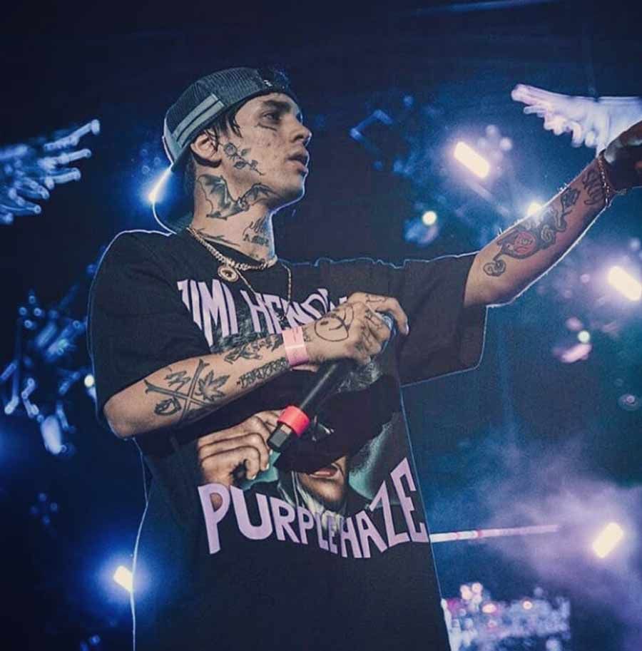 Un hombre está cantando en un micrófono mientras viste una camisa de color violeta.