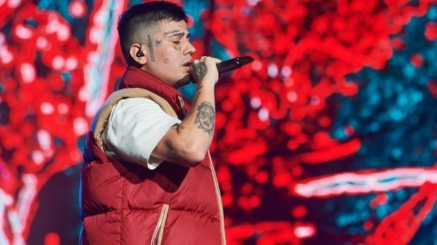 Un hombre con un chaleco rojo está cantando con un micrófono en un escenario.