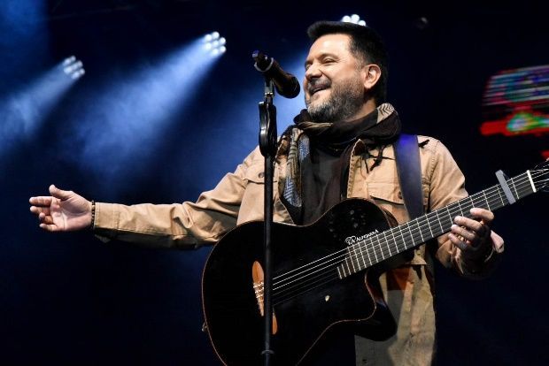 Un hombre toca una guitarra y canta con un micrófono en un escenario.