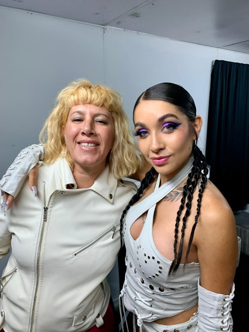 Dos mujeres posan para una foto y una lleva una chaqueta blanca.