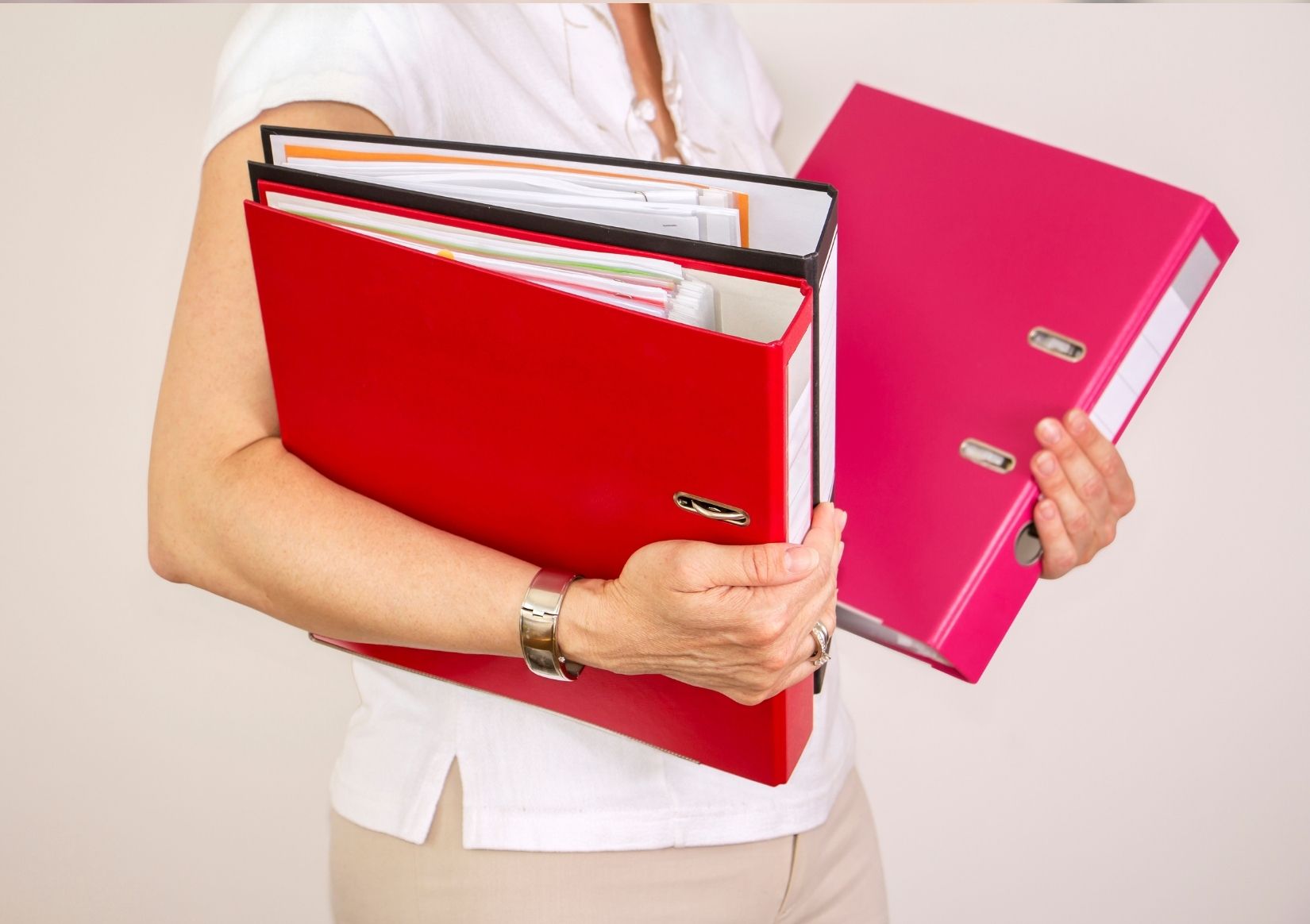 A woman is holding two red binders in her hands.