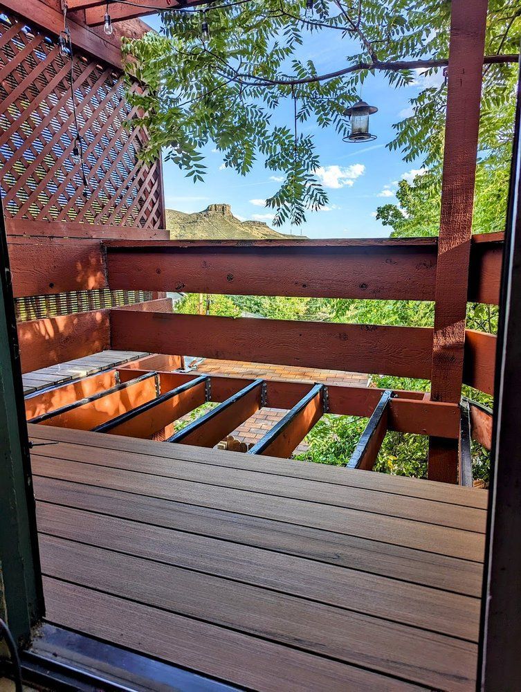 Wooden deck under construction, overlooking a mountain view through trees.