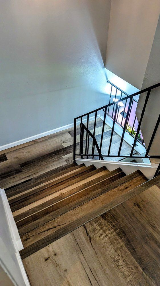 Staircase with wooden steps and black metal railing, viewed from above, with natural light.