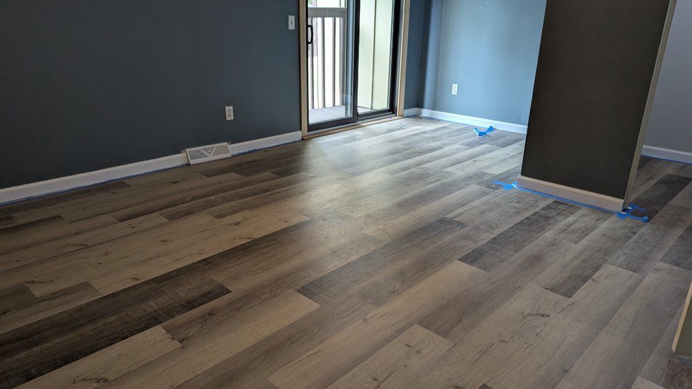 Wooden floor in a room with blue and gray walls. Door visible in the background.