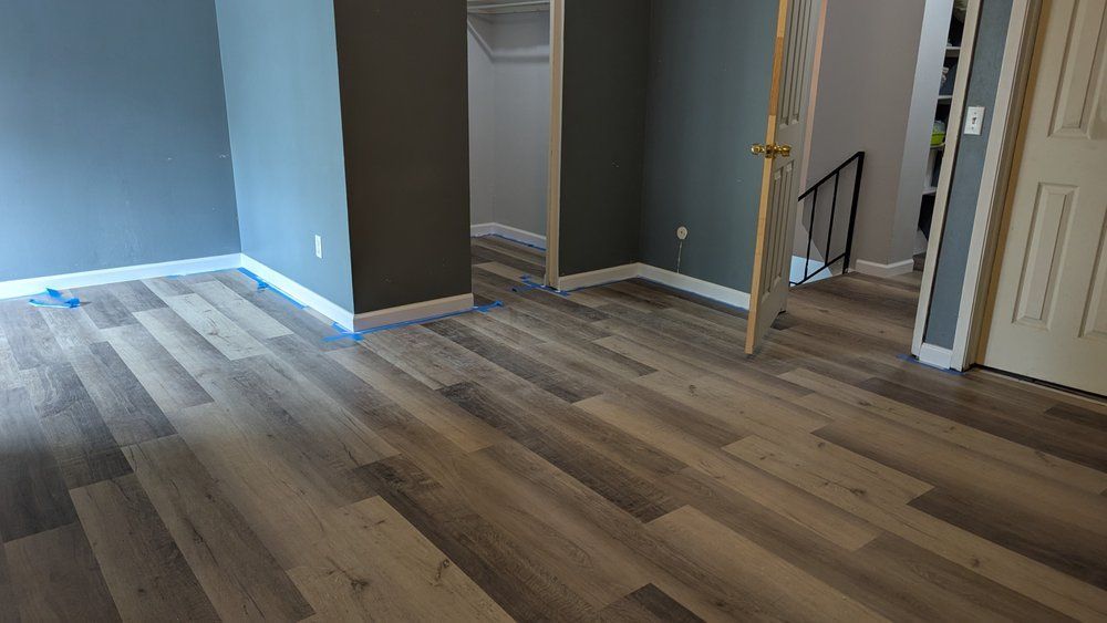 Interior room with gray walls and wood-look flooring. A doorway leads to another room.