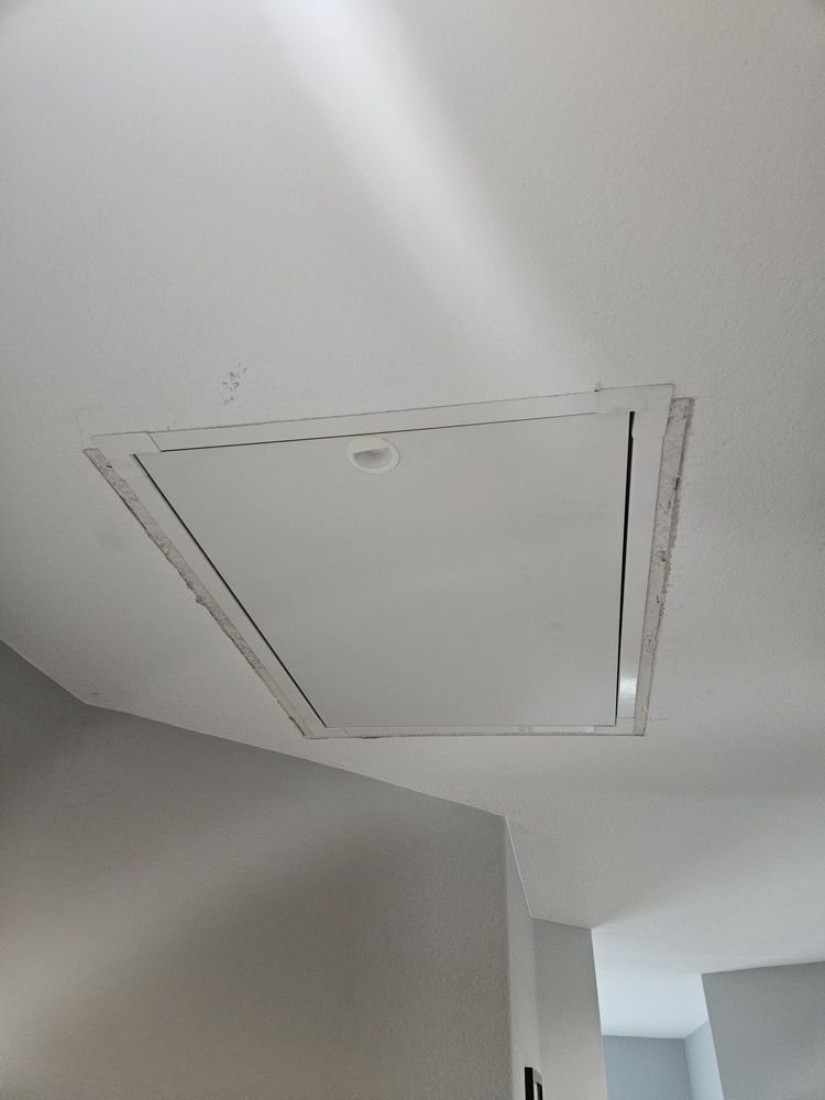 White ceiling with rectangular attic access panel.